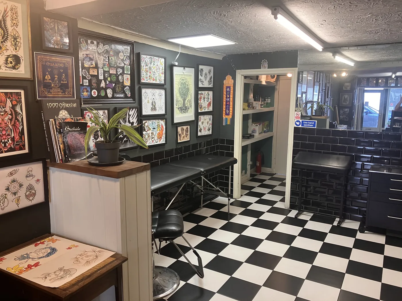 Down the studio: two tattoo beds beneath walls hung with traditional flash sheets.