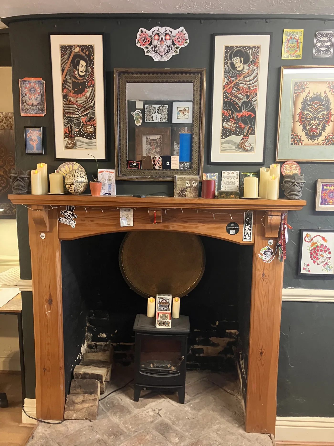 The fireplace corner: candles, a wood-burner and framed samurai prints above the mantel.